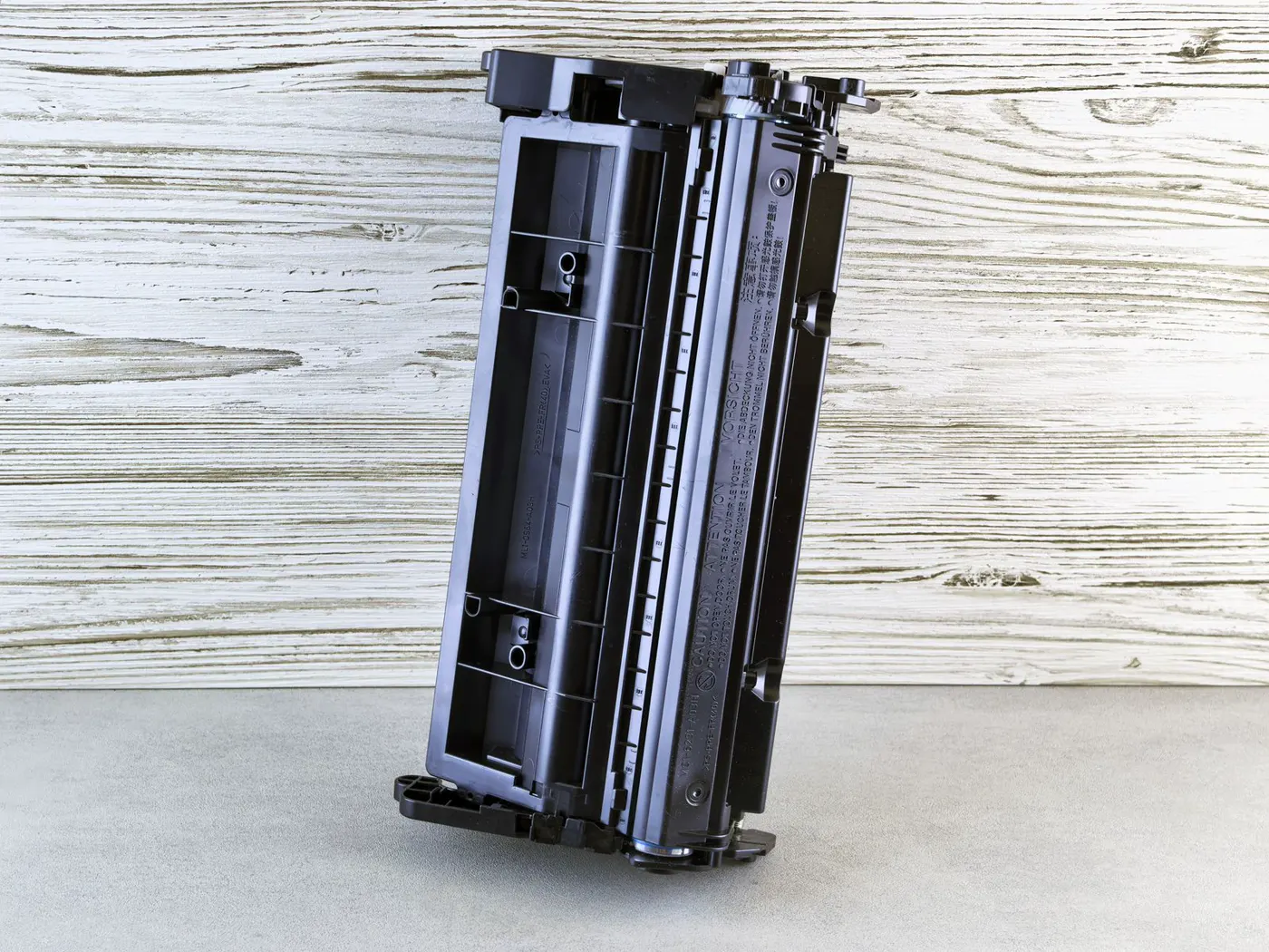 Generic black laser toner cartridge on a wooden surface, no brand marks